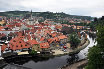Fototapeta na wymiar Summer panorama from the castle fortress wall to the Vltava embankment and the tiled roofs of the houses of the historic part of Cesky Krumlov