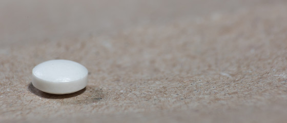 White pills lie on a craft paper with empty space