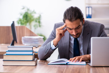 Young male businessman reading books at workplace