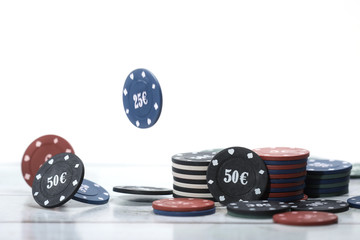 Poker playing chips in focus in front on a wooden table and white background Online gambling. Addiction. Falling poker chips in blur .