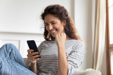 Fototapeta na wymiar Smiling woman holding phone, looking at screen, showing yes gesture close up, celebrating success, satisfied excited girl reading good news in email or social network message, online lottery win