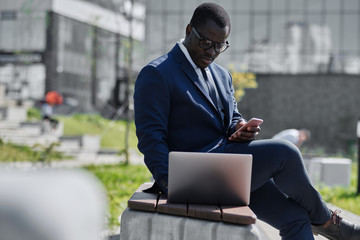 African man working on laptop and smart phone outdoor