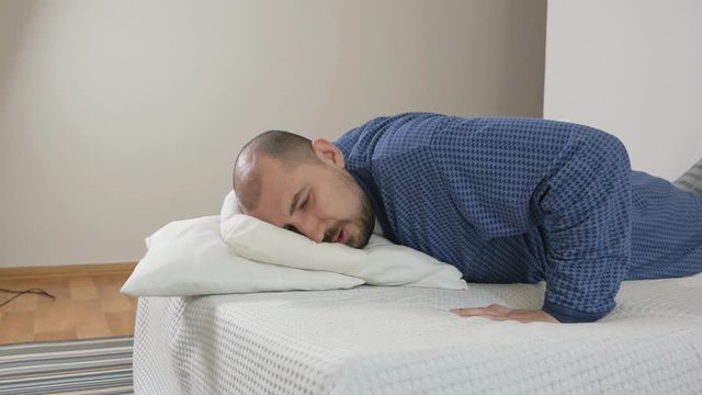 Portrait of a obese man with difficulty doing exercises on the bed. Lazy man and sport