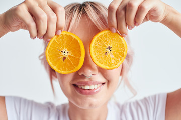 Smiling woman holding oranges at her face like eyes