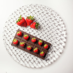 Composition of the plate with chocolate bar and strawberries on top and large strawberries on the...