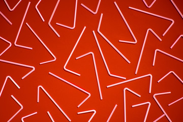 Top view of white plastic straws on red color background creating pattern