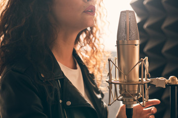 Pretty female singer recording in music studio
