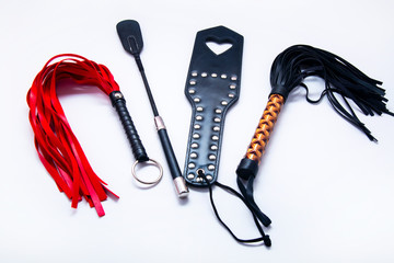 Whip on white background. Accessories for adult sexual games. Toys for BDSM, spanking devices....