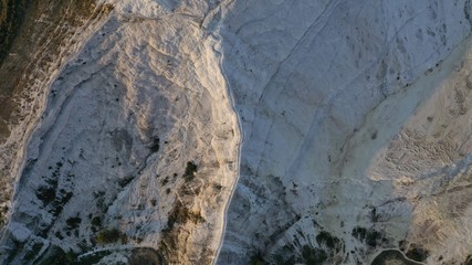 Aerial view of thermal pools hot springs tavertine terraces of Pamukkale natural park, white cotton castle, snow white mountains with carbonate mineral milky pools, Turkey
