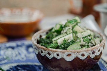 Ukrainian salad with cucumbers in a deep plate on a summer terrace