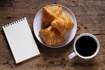 cup of hot coffee  with croissant on dark wooden background.  Working at home concept.