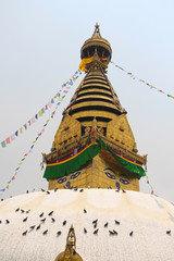 Close up view of the gold colored top of buddhist Swayambhunath stupa, also known among tourists as Monkey Temple, with traditional "Eyes of Buddha" painting. Theme of travel in Kathmandu, Nepal.