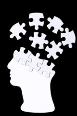 Silhouette of a human head, the top of which are loose pieces of a puzzle