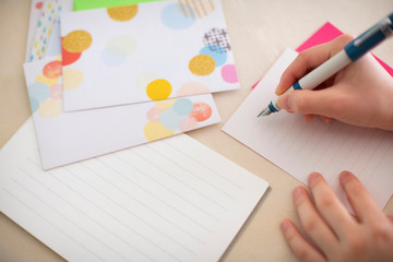 便箋に万年筆で手紙を書こうとしている女の子の手元