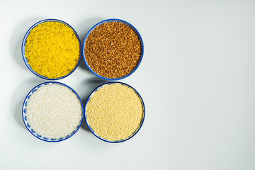 Four bowls with cereals of different types on a white background
