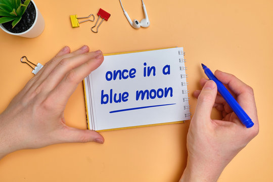 English idiom hand lettering about time - once in a blue moon on wooden blocks.