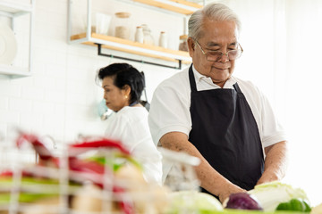 Asian Elderly couple cooking in the home kitchen.