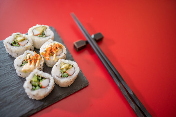 Japanese food,sushi set on blackboard and chopsticks isolated on red background. Copyspace