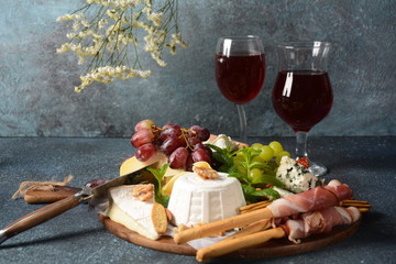 Appetizers table with snacks. Antipasto Cheese Board, salami and prosciutto crudo with grissini bread sticks served with glasses of wine. Traditional French, Spanish or Italian food concept
