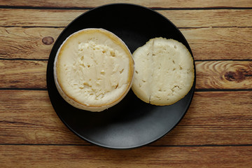 Cheese Torta del Casar open in black plate on rustic wooden table