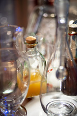 Brown and green old glass bottles on windowsill, with curtain. Closeup, daylight.