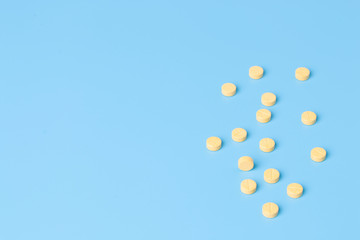 Yellow medical pills on blue background with copy space.