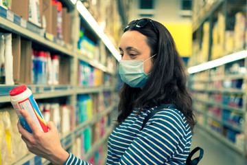 Woman in medical mask choosing goods in a store. Concept of shopping during quarantine at covid-19...