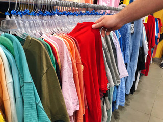 Men's hand pulling out clothing from the rack