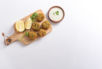 Homemade Tzatziki sauce in a wooden bouwl served with falafel wooden table. With Cilantro and parsley. White background.