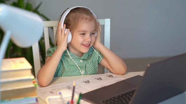 kid girl in headphones listens to music or lesson, distance online learning home