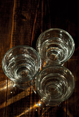 Glasses with alcohol close up. Vodka on a brown wooden background. Glass table from worn shabby boards.