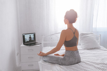 Young woman doing yoga online at home.