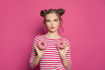 Attractive fashion woman holding donut on vivid pink background