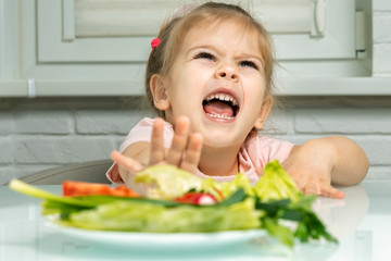 a girl 4 years emotionally repels a plate of vegetables from herself. lack of fruits and vegetables in children's diets