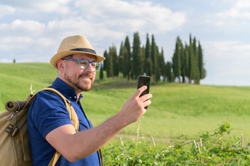 Young beautiful man Hiking in Tuscany and Italian medieval towns with a backpack