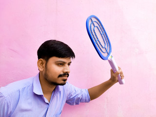 young man holding a Electric mosquito swatter for hit and shock mosquito on pink background...