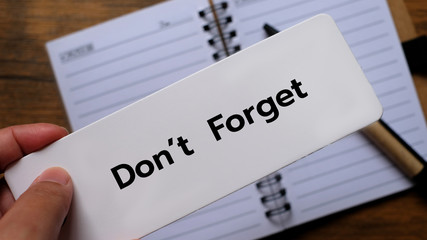 Don't forget text on sticky note on work desk, reminder concept.