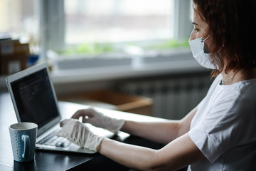 a woman in a mask and gloves works on a laptop, a doctor during the pandemic