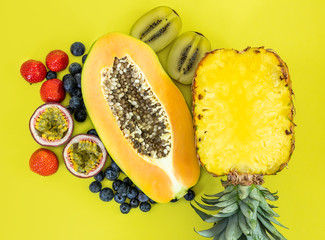 Flat lay of tropical fruits on a yellow background. Summer concept. Pineapple, papaya, passion...