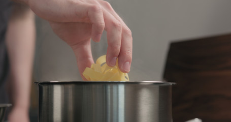 man hand put fettuccine pasta in saucepan with boiling water
