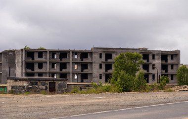 Fototapeta na wymiar Facade of abandoned grey multi-storey soviet panel building