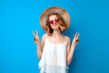 summer concept. portrait of a girl in a sun hat and glasses on a blue isolated background, a woman in summer clothes on vacation