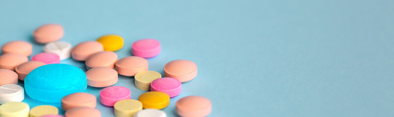 Fototapeta na wymiar Pile of colorful pills on a blue background