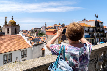 Faceless woman tourist take photos of aerial cityscape view of old town of Porto city during the sunny day in Portugal