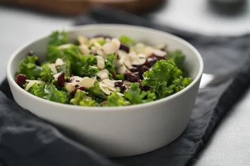 Foto op Canvas Salad with kale, cranberries and almond flakes in white bowl on linen napkin © GCapture