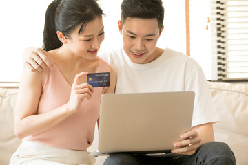 Online Shopping. Happy Smiling Couple Using Credit Card to Internet Shop on-line. Young couple with Laptop Computer and Credit Card buying online. Christmas and New Year Gifts. e-shopping