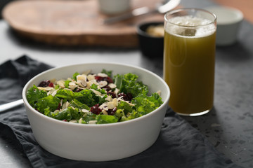 Salad with kale, cranberries and almond flakes in white bowl on linen napkin with copy space