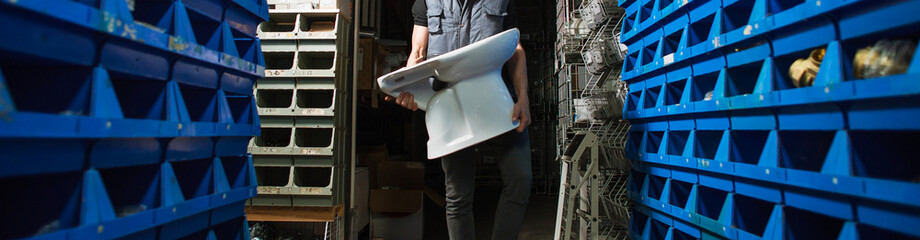 Widescreen image, delivery, a man in a warehouse carries a toilet in his hands
