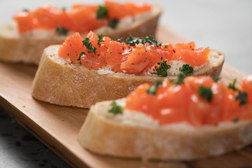 Bruschettas with salmon and cream cheese on olive wood board