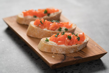 Bruschettas with salmon and cream cheese on olive wood board